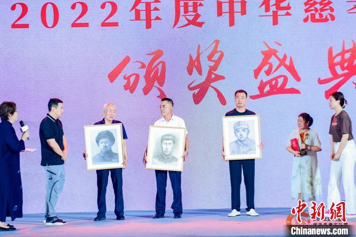 2022第八届中华慈孝文化节开幕式暨年度中华慈孝人物颁奖盛典现场，三位烈士家属手捧各自亲人的素描画像 主办方 供图